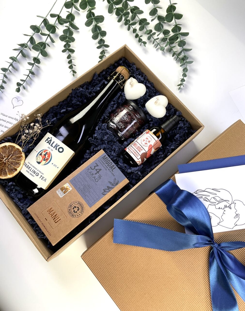 Romantyczny prezent dla Pary Młodej z bezalkoholowym winem, olejkiem do masażu, czekoladą, świecami w kształcie serca oraz elegancką kartką z personalizacją.