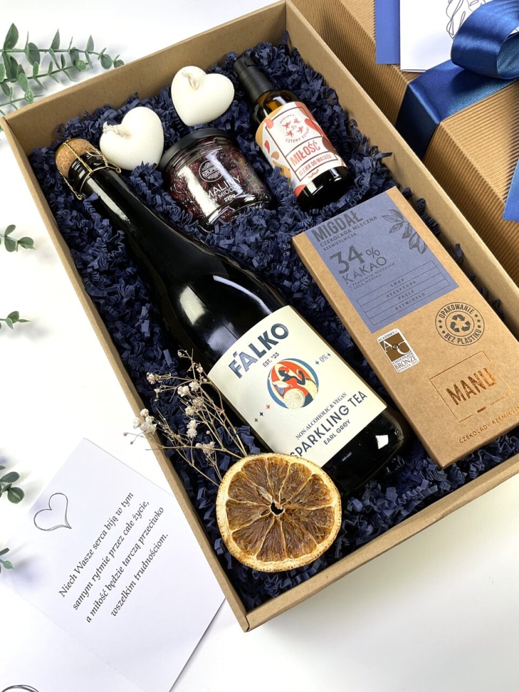Pomysł na wyjątkowy prezent ślubny. Elegancki zestaw prezentowy z bezalkoholowym winem, słodkościami, olejkiem do masażu i personalizowaną kartką.