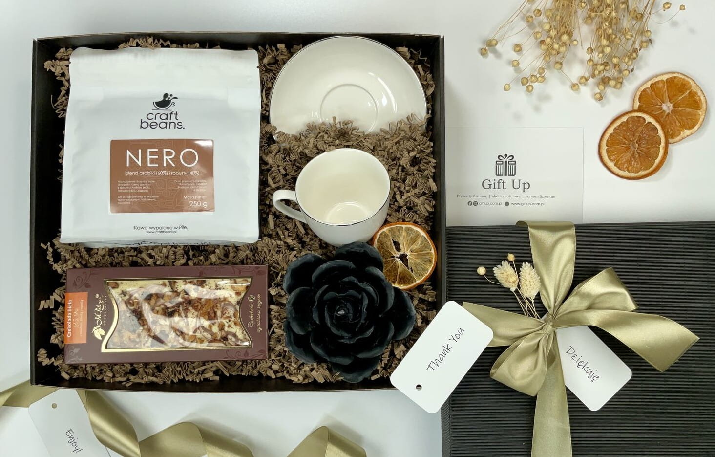 zestaw box kosz prezentowy firmowy z kawą ziarnistą porcelanową białą filiżanką ze złotym rantem naturalną czarną świecą z wosku pszczelego i przepyszną ręcznie robioną białą czekoladą z miodem cynamonem i jabłkami