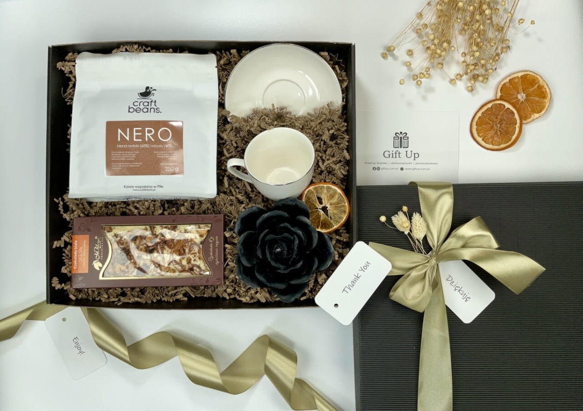zestaw box kosz prezentowy firmowy z kawą ziarnistą porcelanową białą filiżanką ze złotym rantem naturalną czarną świecą z wosku pszczelego i przepyszną ręcznie robioną białą czekoladą z miodem cynamonem i jabłkami